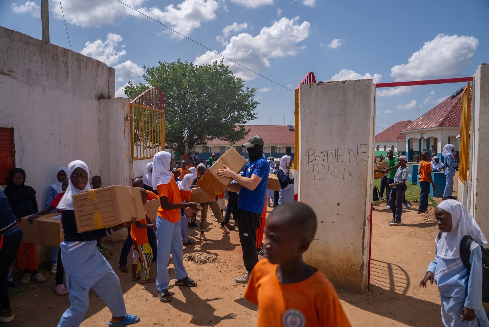 Pupils and helpers carrying school supplies onto campus