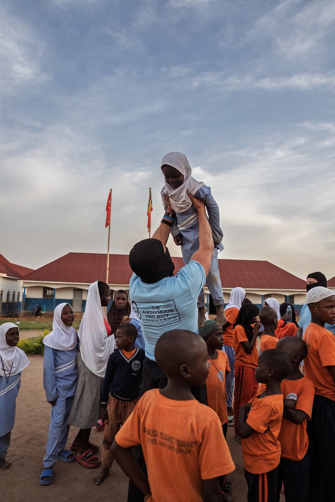An adult lifting a pupil during a joyful moment on campus