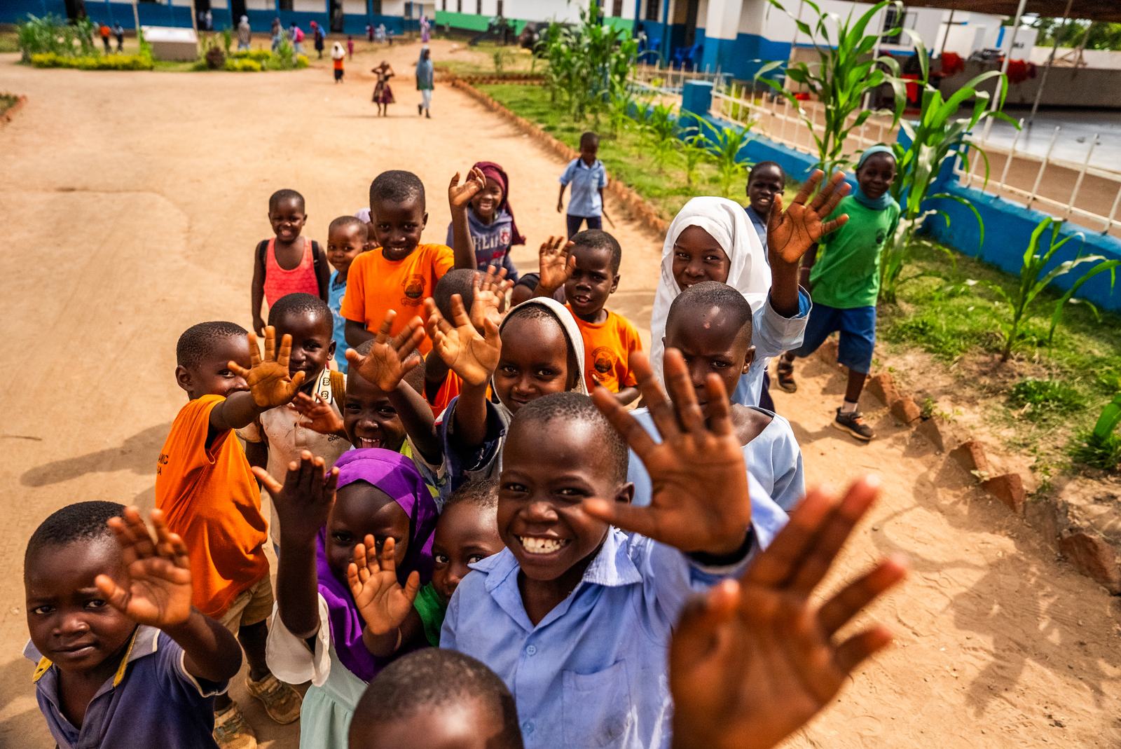 Smiling pupils waving in the school grounds