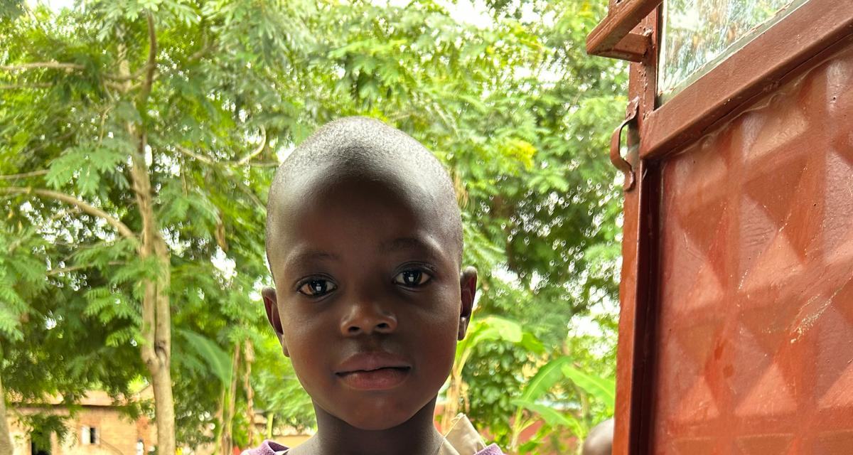 A smiling boy beside a red door