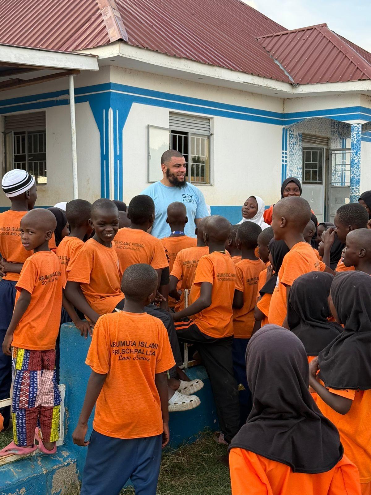 A volunteer standing with pupils outside a school building