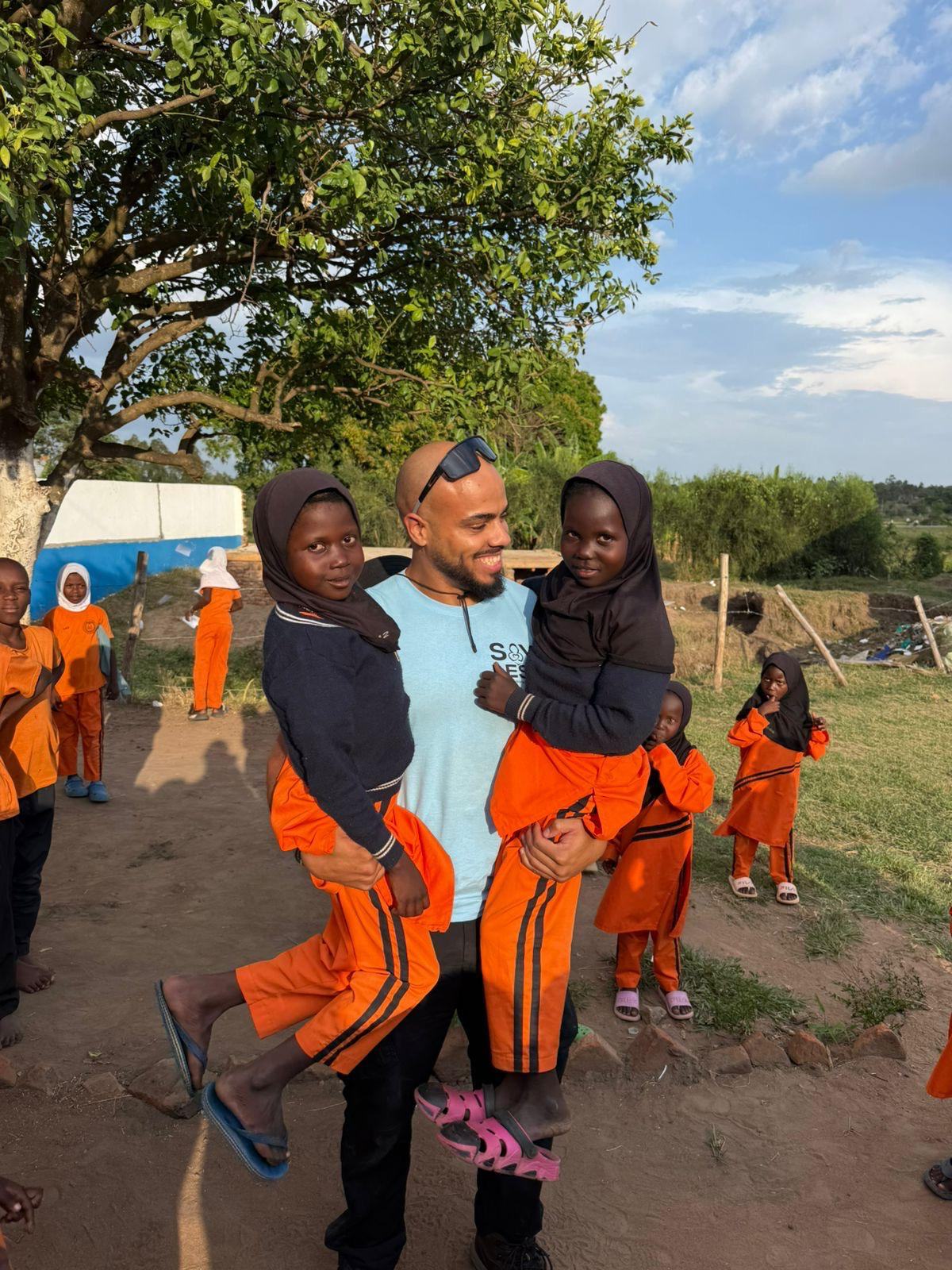 A volunteer holding two pupils in school uniform